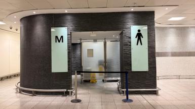 A men's toilet with a block in front of the entrance.