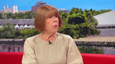 A woman red hair cut into a bob sits on the BBC Breakfast sofa, wearing a beige long-sleeved blouse.