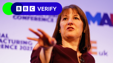 Chancellor Rachel Reeves gesturing with her right hand while speaking at the National Manufacturing Conference. The BBC Verify logo appears in the top left corner of the image.