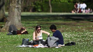 People sitting in a park in the sunshine having a picnic