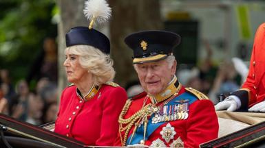 Queen Camilla and the King in military uniforms as they sit in a carriage and process down the Mall for Trooping the Colour