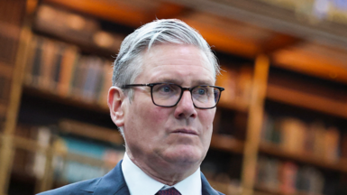 Keir Stsramer inside the British Museum looking serious wearing a suit and tie, head and top of shoulders shown. 