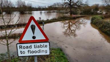 Trees and hedgerows are seen above flooded fields and roads near Upton-upon-Severn