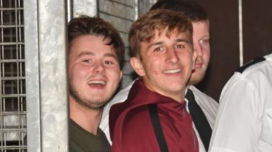 Albert Bowers (left) and Jessie Cole (centre), smiling, appearing to laugh or mock the assembled media, as they leave Reading Magistrates Court following an appearance in relation to the death of PC Andrew Harper. 