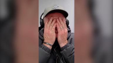 Wayne Rooney is wearing a cap and has his hands to his face.