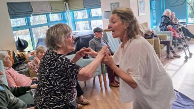 Siri Wigdel yn dawnsio gydag un o breswylwyr cartref i'r henoed
