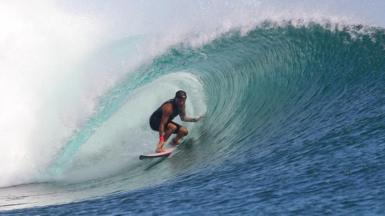 Surfer Matt Grainger rides a wave. He is wearing a black cap on his head.