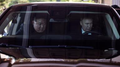 Mr Putin behind the wheel of a car with Mr Kim next to him in the passenger seat
