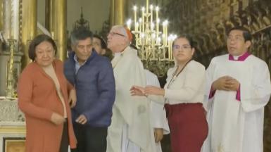 Priest and churchgoers looking around with concerned expressions in cathedral