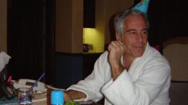 Epstein sat a table wearing a party hat. 