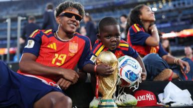Lamine Yamal smiles for a photo with his little brother Keyne following Spain's win in the FIFA World Cup. Kenye is holding the World Cup trophy.