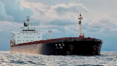 Chinese ship Yi Peng Three in the Kattegat strait off Denmark. It has a black hull and is a cargo ship, so its body is long and low. 