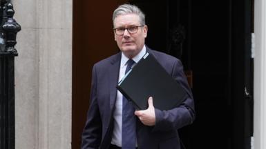 Sir Keir Starmer pictured leaving Number 10, holding a black folder.