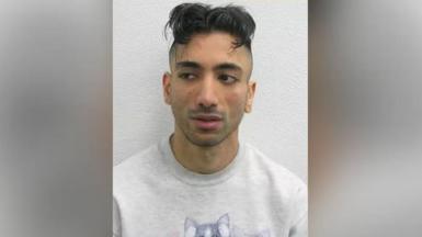 A mugshot of Jacky Jhaj, wearing a white jumper.