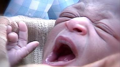 A close-up of a newborn baby yawning.
