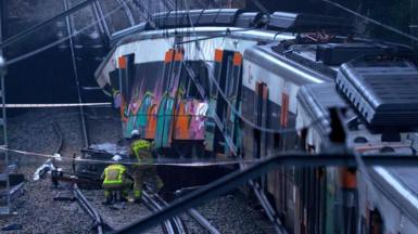 Firefighters are seen inspecting a derailed commuter train carriage 