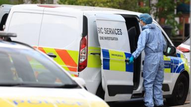 A forensics officer opens the door of a police van while wearing a hazmat suit at the scene in Finchley on Wednesday.