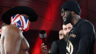 Derek Chisora in a UK flag around his face, faces off with Deontay Wilder