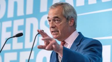Nigel Farage looks up and away from camera with two small microphones in shot against a light blue background, as he delivers a speech at a press conference on 10 July in London.