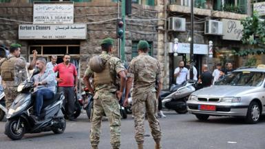 Two Lebanese soldiers stand guard near a hospital, as traffic passes by