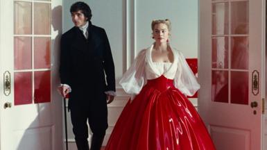 Jacob Elordi in a black suit as Heathcliff and Margot Robbie as Cathy in a white and red PVC dress