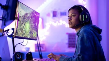 Stock photo of a young black female gamer playing at night