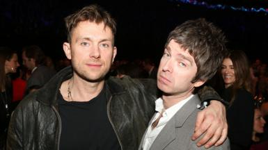 Damon Albarn wearing a black leather jacket with his arm around Noel Gallagher at the Brit Awards 2013