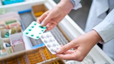 Pharmacists holding pills in hands above drawer with medicines. Close up of hands, unrecognisable person.
