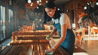Woman working in a restaurant cleaning tables