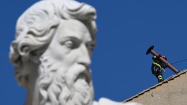 Image shows fire service worker fitting a chimney to the top of the Sistine Chapel ahead of the conclave 
