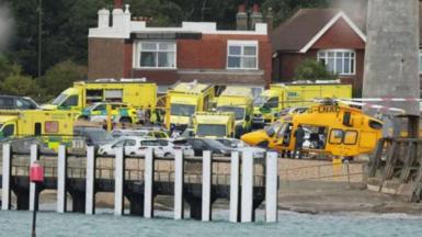 ambulances and a helicopter lined up by the shore