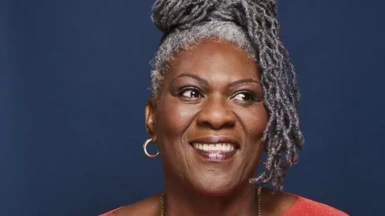A woman with grey dreadlocks smiles as she looks away from the camera for a portrait photo