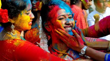 People react as fellow students throw colored powder in her face at the Holi or Color Festival Celebration near Kolkata, India, on March 13, 2025.