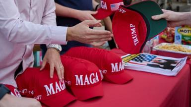 Red hats with Donald Trump's Maga logo are handed out at an event