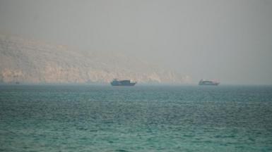 Two vessels are seen in the Strait of Hormuz, surrounded by rocky mountains, from Musandam, Oman