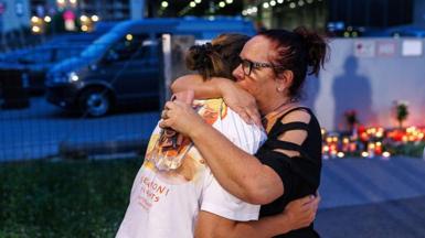 People embrace as others light candles at the school on June 10, 2025 in Graz, Austria.