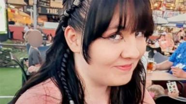 A girl with dark hair and a pink top smiles at the camera.