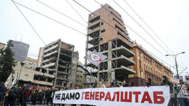 A banner saying "we won't surrender the Generalstab" is held outside the ruins in Belgrade
