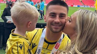 Owen, Jessica and Xavier on the pitch, with Jessica giving Owen a kiss on the cheek