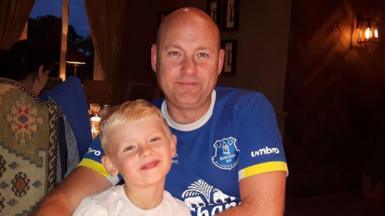 A man and boy smile at the camera 