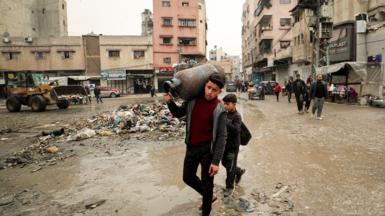 A young boy walks through a street in Gaza City on 3 February while carrying a tank of water