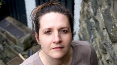 Ruth has dark hair and is looking directly at the camera.