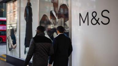 Two men walk past an M&S store