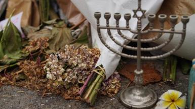 A menorah pictured alongside a wilting bunch of flowers at the Bondi memorial