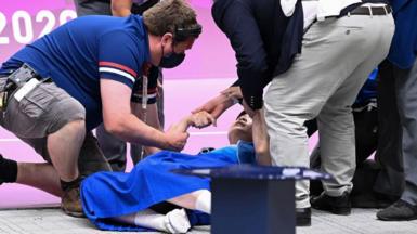 Athlete collapsed on the floor with people trying to help