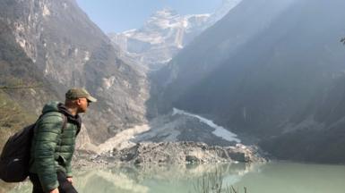 BBC World Service environment correspondent Navin Singh Khadka trekking with mountains visible behind him