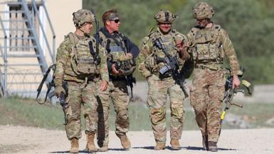 US troops walking during a training exercise in Germany. They carry rifles and wear camo