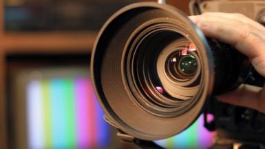 Close-up shot of professional video camera, with its lens zooming in.