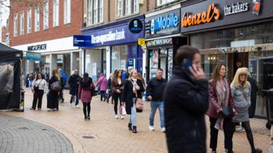 A scene of a high street in Chelmsford earlier this week shows people walking down the street and a man on his phone with shops lining the street.