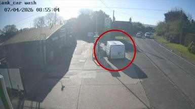 White van parked on petrol forecourt next to fuel pump  